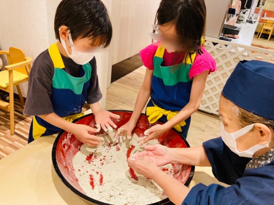 蕎麦作り体験で指についた生地を取る子ども達