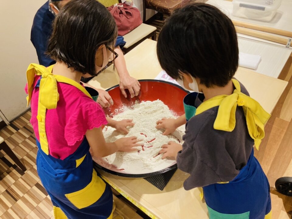 蕎麦作り体験で粉を混ぜる子どもたち